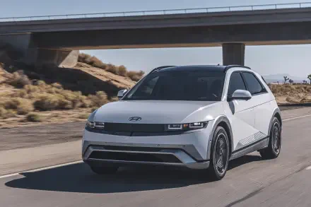A sleek white Hyundai IONIQ 5 drives along a highway under a bridge, showcasing its modern design. This image serves as a sharp 4K Ultra HD desktop wallpaper.
