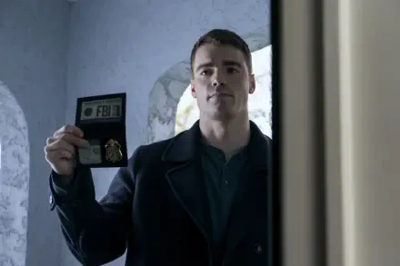 Gabriel Basso as an FBI agent from the TV show The Night Agent, displaying his badge with a serious expression against a backdrop that suggests tension and intrigue.