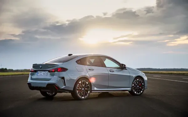 A sleek BMW M235 xDrive Gran Coupe parked on an open road, with a stunning sunset in the background, showcasing its dynamic design and performance features.