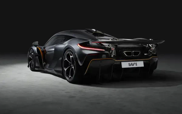 A sleek McLaren W1 vehicle displayed in a striking black finish, showcasing its aerodynamic design against a dark background. A stunning 4K Ultra HD wallpaper for car enthusiasts.