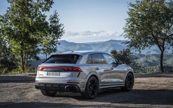 A sleek Audi RS Q8 parked in a scenic landscape, showcasing its modern design against a backdrop of mountains and trees, captured in 4K Ultra HD quality.