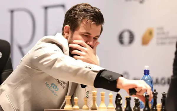 Magnus Carlsen, a renowned chess player, intensely contemplates his next move while seated at a chessboard, showcasing the strategic depth of the sport in this HD desktop wallpaper.