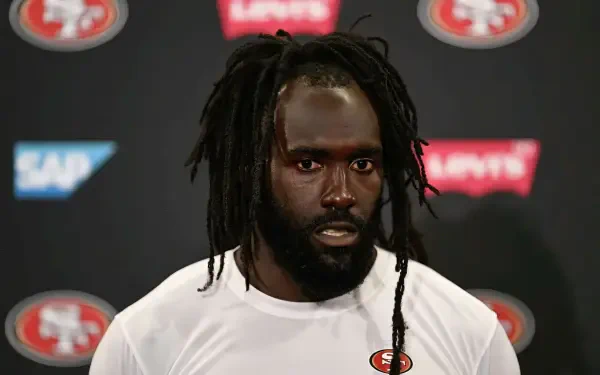 De'Vondre Campbell speaks during a San Francisco 49ers press conference, showcasing team spirit with the logo in the background. HD wallpaper capturing the intensity of football.