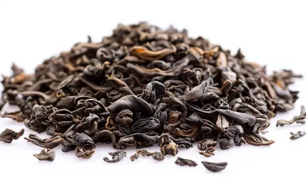 A pile of dry, curled oolong tea leaves on a white background, showcasing rich textures and tones, designed as a stunning 4K Ultra HD PC desktop wallpaper.