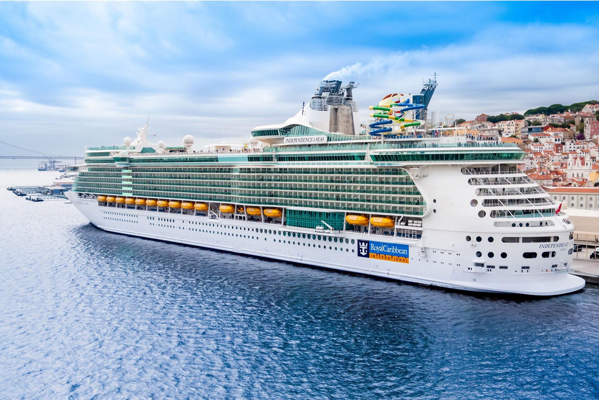 A stunning Royal Caribbean cruise ship docked in serene waters, showcasing its impressive architecture and vibrant amenities against a backdrop of blue skies.