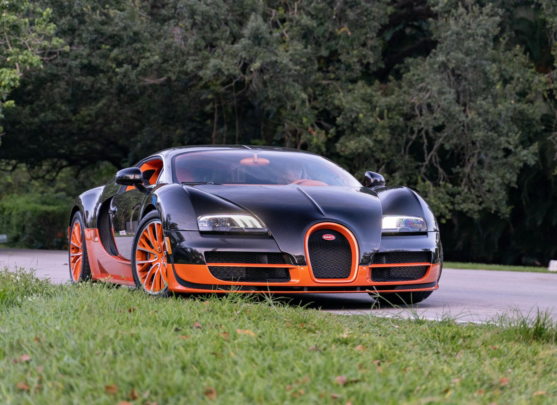 Black and orange Bugatti Veyron car parked by trees on a road, shown in crisp detail as a 4K Ultra HD PC desktop wallpaper and background.