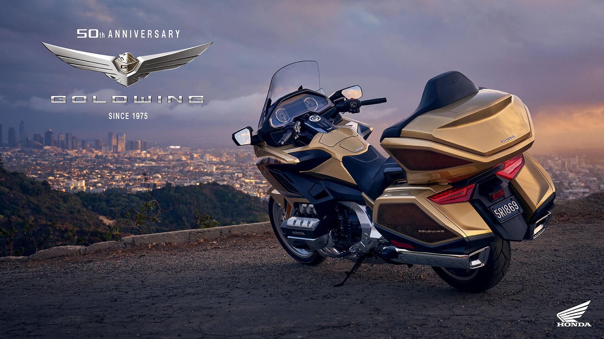 A 25YM Honda GL 1800 Gold Wing motorcycle parked on a scenic overlook, showcasing its sleek design against a backdrop of a city skyline during sunset.