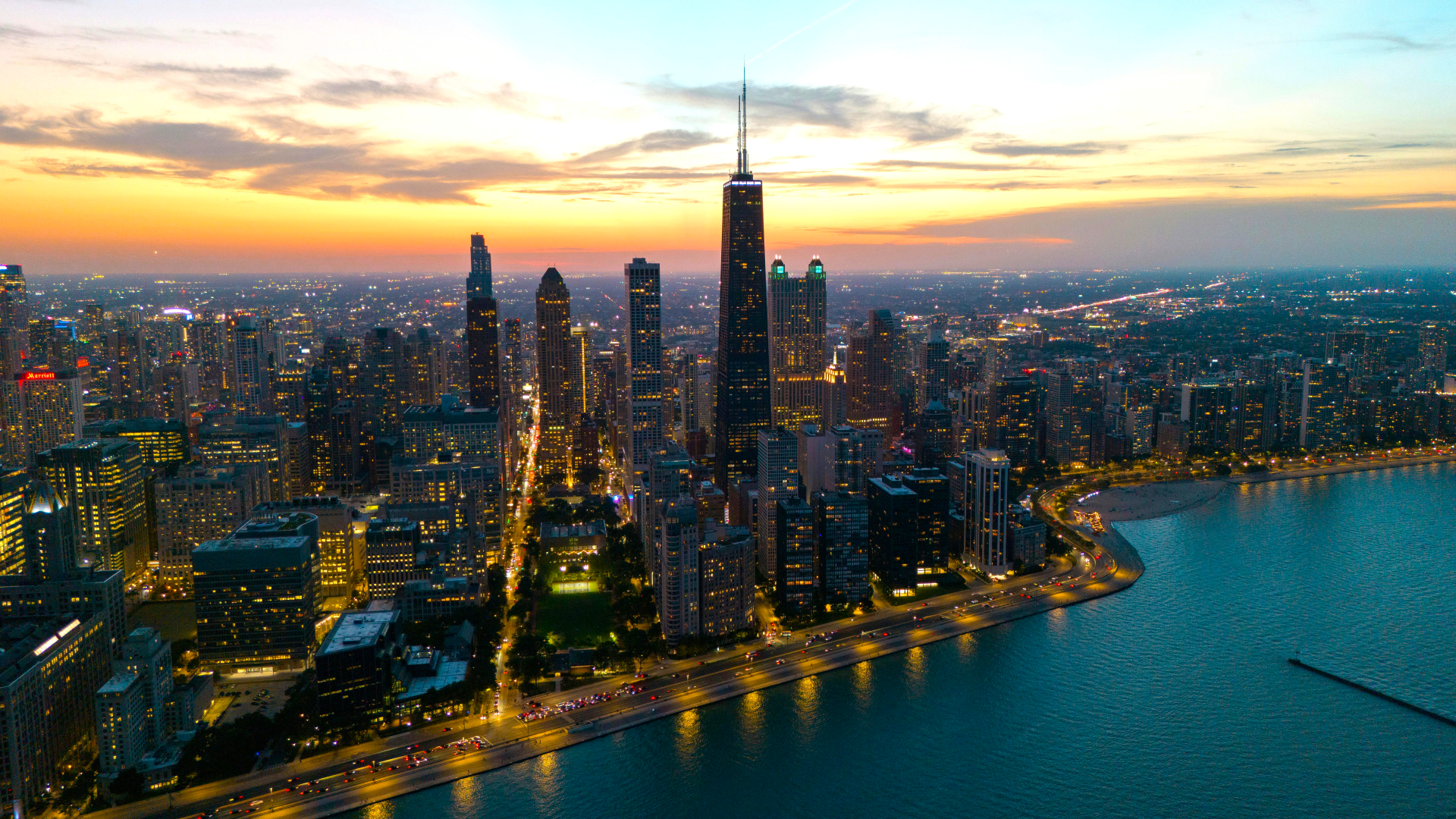 A stunning 4K Ultra HD cityscape of Chicago, Illinois, showcasing illuminated skyscrapers along the lakeshore at sunset in the USA.