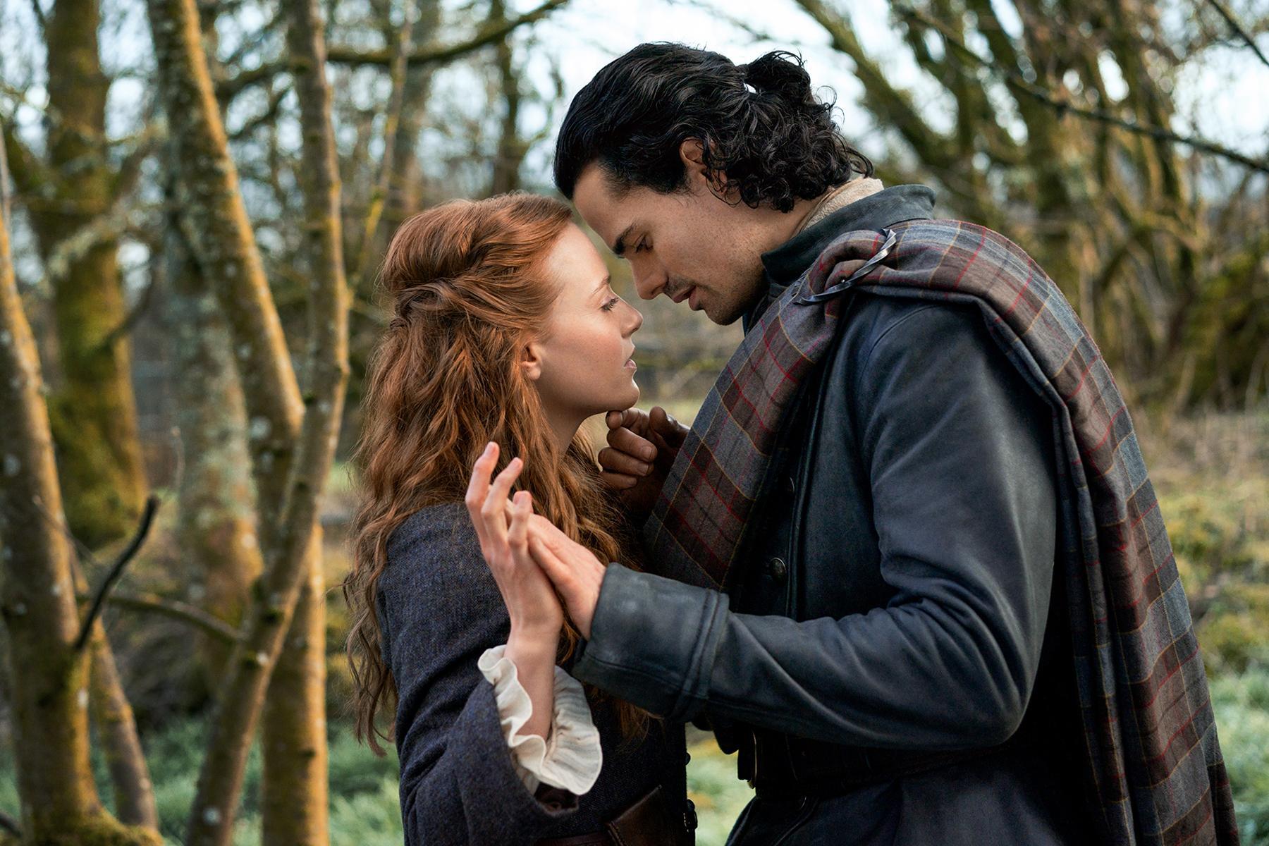 HD desktop wallpaper featuring a tender moment between two characters from the TV show Outlander: Blood of My Blood, set in a wooded outdoor scene.