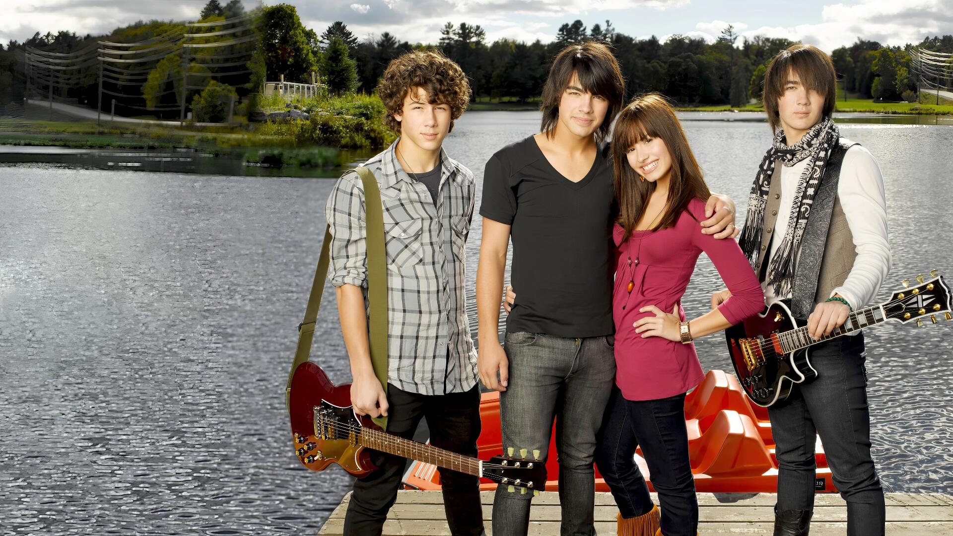 HD PC desktop wallpaper of four young musicians with guitars posing on a lakeside dock — promotional movie image for Camp Rock.