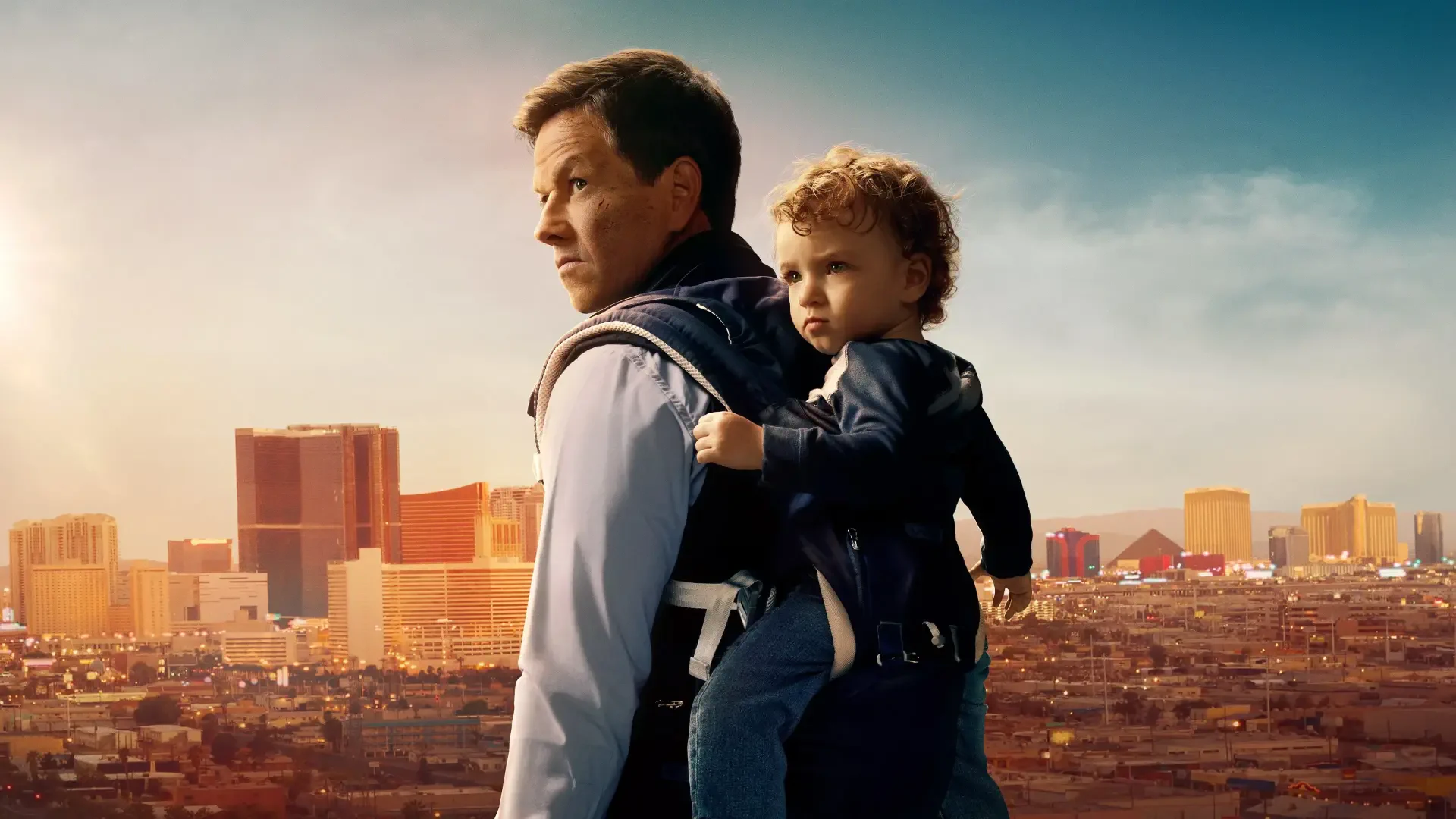 4K Ultra HD PC desktop wallpaper for The Family Plan: a man carrying a toddler in a carrier, gazing over a sunlit city skyline.