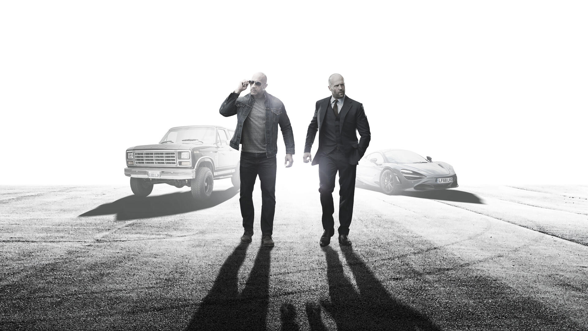 Fast & Furious Presents: Hobbs & Shaw HD PC desktop wallpaper — black-and-white image of two men walking toward the camera with a truck and car behind, casting long shadows.