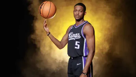 A Sacramento Kings player skillfully balances a basketball on his finger against a vibrant yellow backdrop, showcasing a dynamic and striking NBA sports theme.