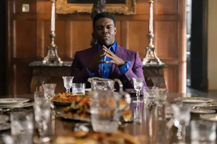 A still from the TV show Ted Lasso, featuring Sam Richardson seated at an elegant dining table, exuding confidence, surrounded by dishes and glasses. 8K Ultra HD quality background.