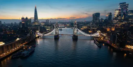 Cityscape of London at dusk featuring Tower Bridge illuminated over the Thames, surrounded by skyscrapers in a 4K Ultra HD desktop wallpaper background.