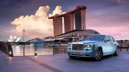 Luxury car parked by a waterfront with a billionaire's iconic cityscape in the background, captured in a stunning HD desktop wallpaper.