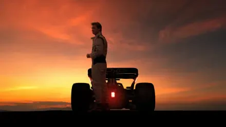 Brad Pitt stands beside an F1 car at sunset in this 8K Ultra HD F1 (2025) desktop wallpaper, capturing a dramatic and cinematic racing moment.