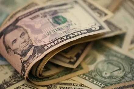 Close-up HD desktop wallpaper featuring a rolled US dollar bill with Abraham Lincoln's portrait, surrounded by additional scattered currency notes.