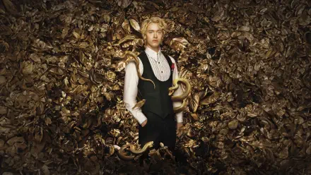 8K Ultra HD PC desktop wallpaper for The Hunger Games: The Ballad of Songbirds & Snakes — blond youth in a formal vest stands amid coiled golden snakes and ornate metallic leaves.