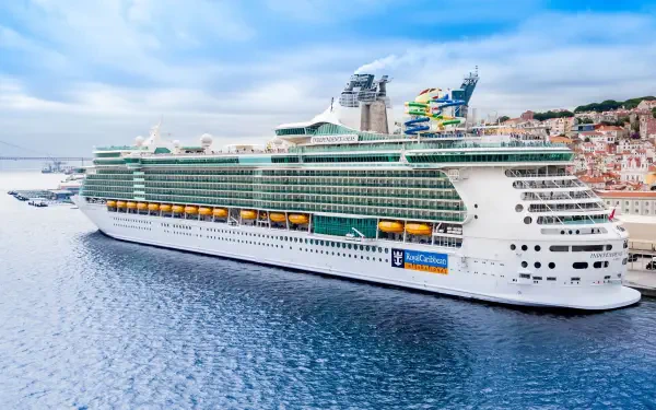 A stunning Royal Caribbean cruise ship docked in serene waters, showcasing its impressive architecture and vibrant amenities against a backdrop of blue skies.