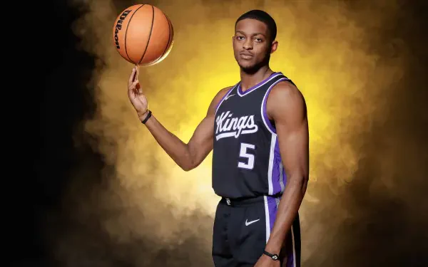 A Sacramento Kings player skillfully balances a basketball on his finger against a vibrant yellow backdrop, showcasing a dynamic and striking NBA sports theme.