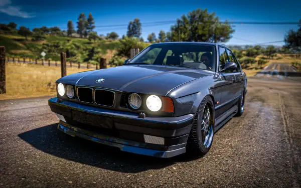 A stunning 4K Ultra HD wallpaper featuring a BMW E34 from Forza Horizon 5, showcasing the car's sleek design against a picturesque outdoor backdrop.