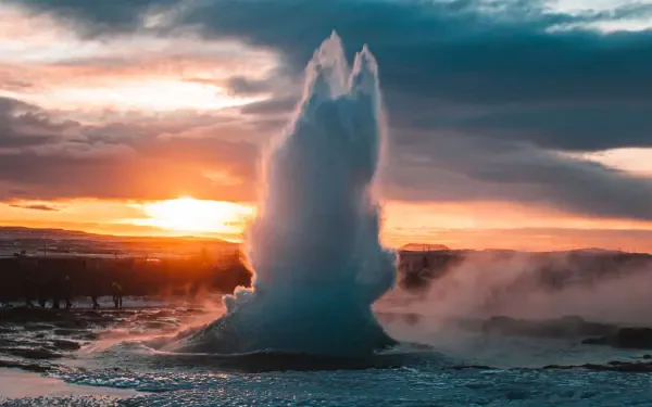 Strokkur Geyser erupts against a dramatic sunset in Iceland, showcasing nature's power and beauty in stunning 4K Ultra HD. Perfect for a desktop wallpaper.