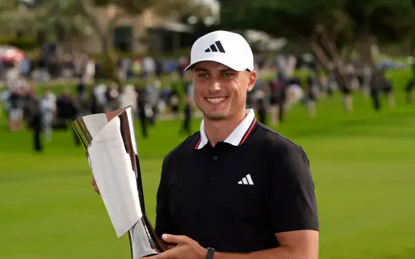 Ludvig Åberg smiles while holding a trophy on a vibrant golf course, showcasing his achievement in the sport. This 4K Ultra HD image serves as a striking desktop wallpaper.