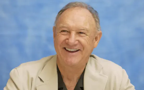 A smiling Gene Hackman, captured in a light-colored suit against a soft blue background. This HD image serves as a vibrant desktop wallpaper.