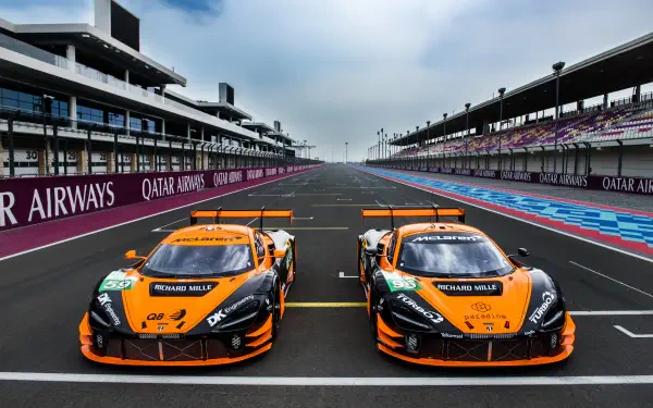 A dynamic 4K Ultra HD image featuring two McLaren GT3 EVO cars lined up on a racetrack, showcasing their striking orange livery against a modern racing backdrop.
