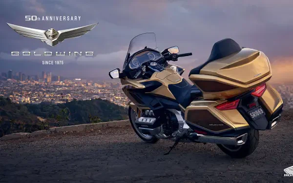 A 25YM Honda GL 1800 Gold Wing motorcycle parked on a scenic overlook, showcasing its sleek design against a backdrop of a city skyline during sunset.