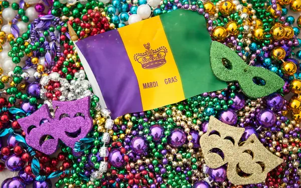 A vibrant celebration of Mardi Gras, featuring a flag, colorful beads, and festive masks, creates a lively backdrop for this HD desktop wallpaper and background.