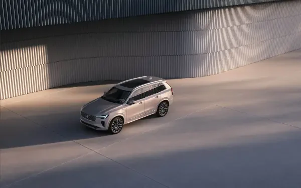 A sleek Volvo XC90 Facelift parked on a modern, textured surface, captured in stunning 4K Ultra HD, showcasing its elegant design and stylish presence.