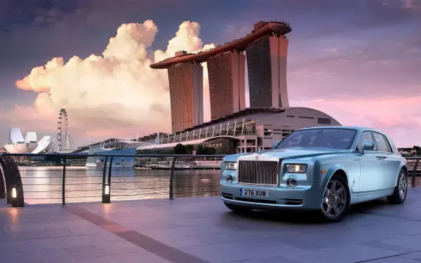 Luxury car parked by a waterfront with a billionaire's iconic cityscape in the background, captured in a stunning HD desktop wallpaper.