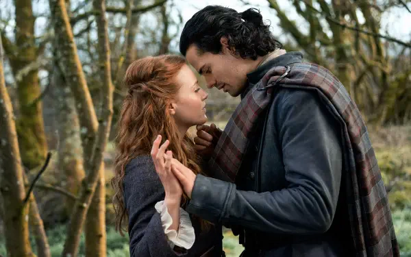 HD desktop wallpaper featuring a tender moment between two characters from the TV show Outlander: Blood of My Blood, set in a wooded outdoor scene.