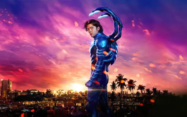 Blue Beetle in glowing sci‑fi armor stands on a rooftop at sunset, city skyline and palm trees below; vibrant 4K Ultra HD desktop wallpaper with neon purple and orange sky.