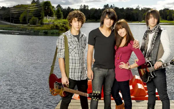 HD PC desktop wallpaper of four young musicians with guitars posing on a lakeside dock — promotional movie image for Camp Rock.