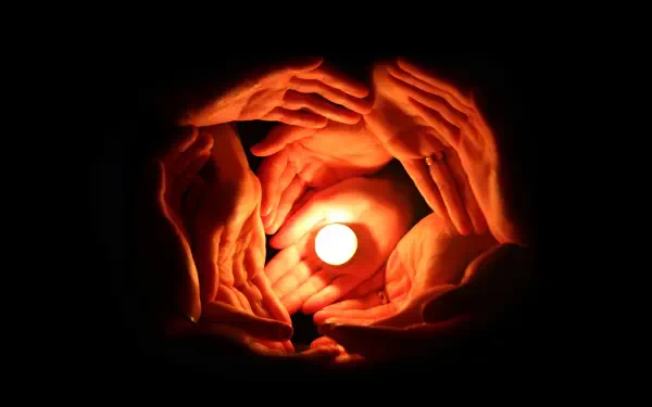 Multiple hands circle a glowing candle, symbolizing family, love and togetherness — HD PC desktop wallpaper/background.
