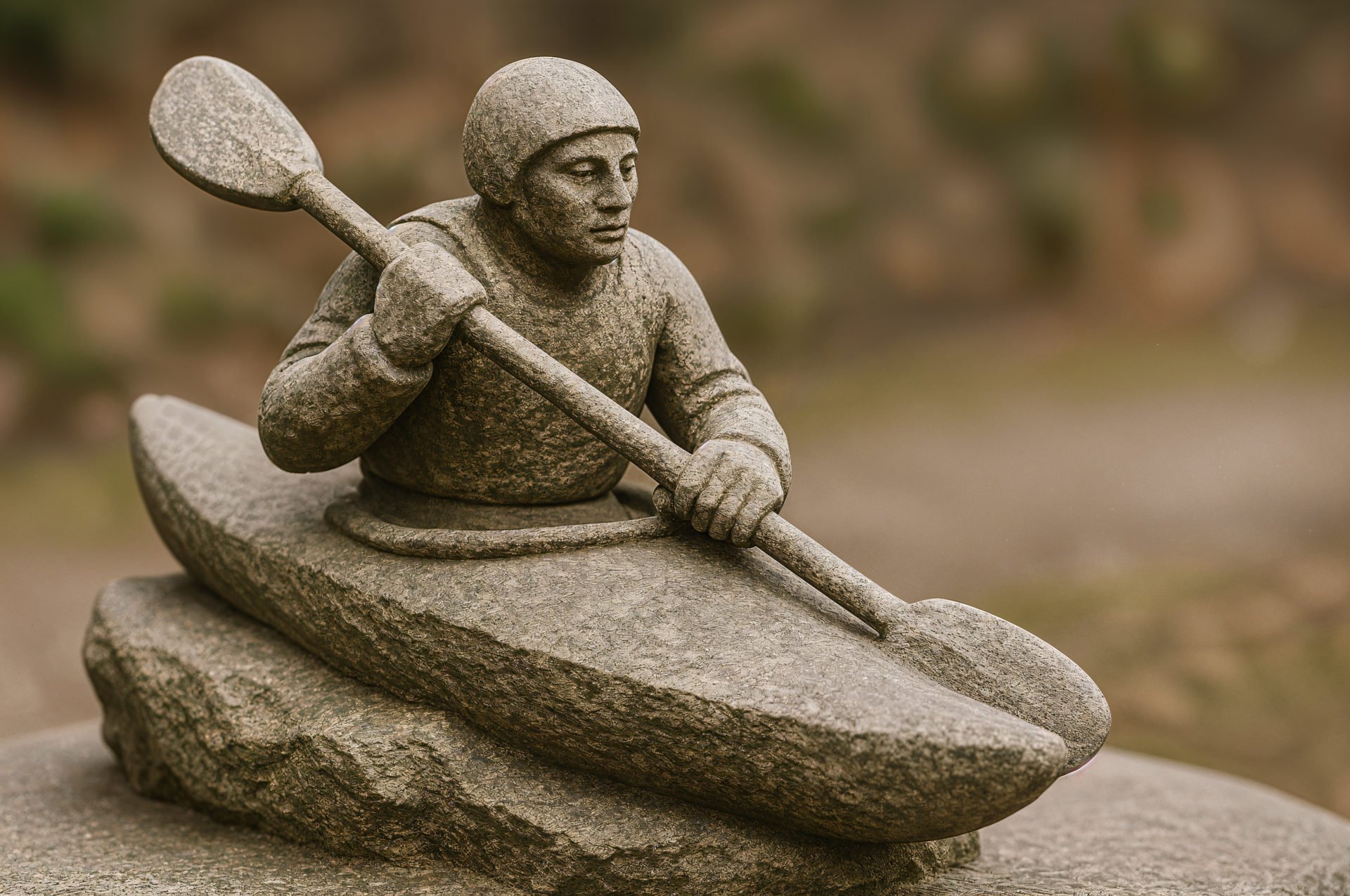 Stone sculpture of a kayaker paddling a carved kayak against a softly blurred natural background — 4K Ultra HD PC desktop wallpaper and background.