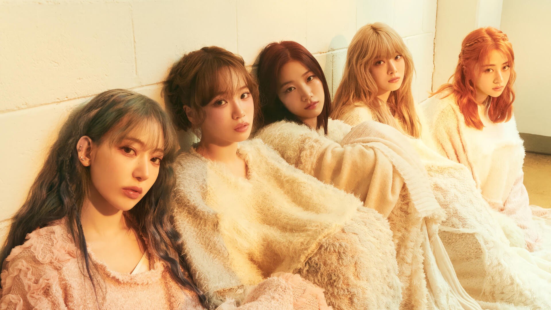 Five women in soft cream outfits seated against a pale wall in warm golden light — serene group portrait, 4K Ultra HD PC desktop wallpaper and background.