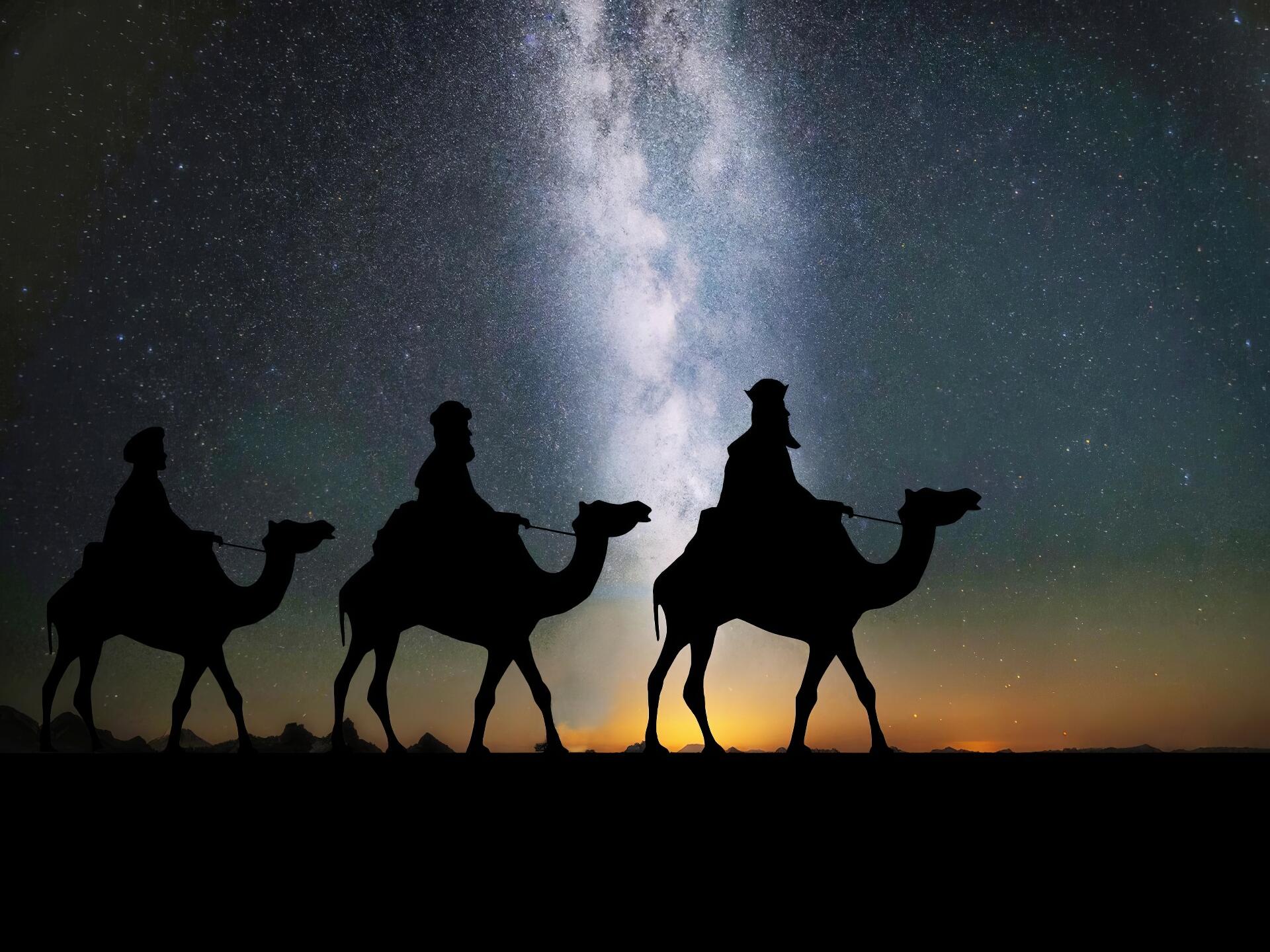 Silhouetted Biblical Magi on camels crossing a desert beneath a brilliant starry sky and Milky Way — HD PC desktop wallpaper/background.