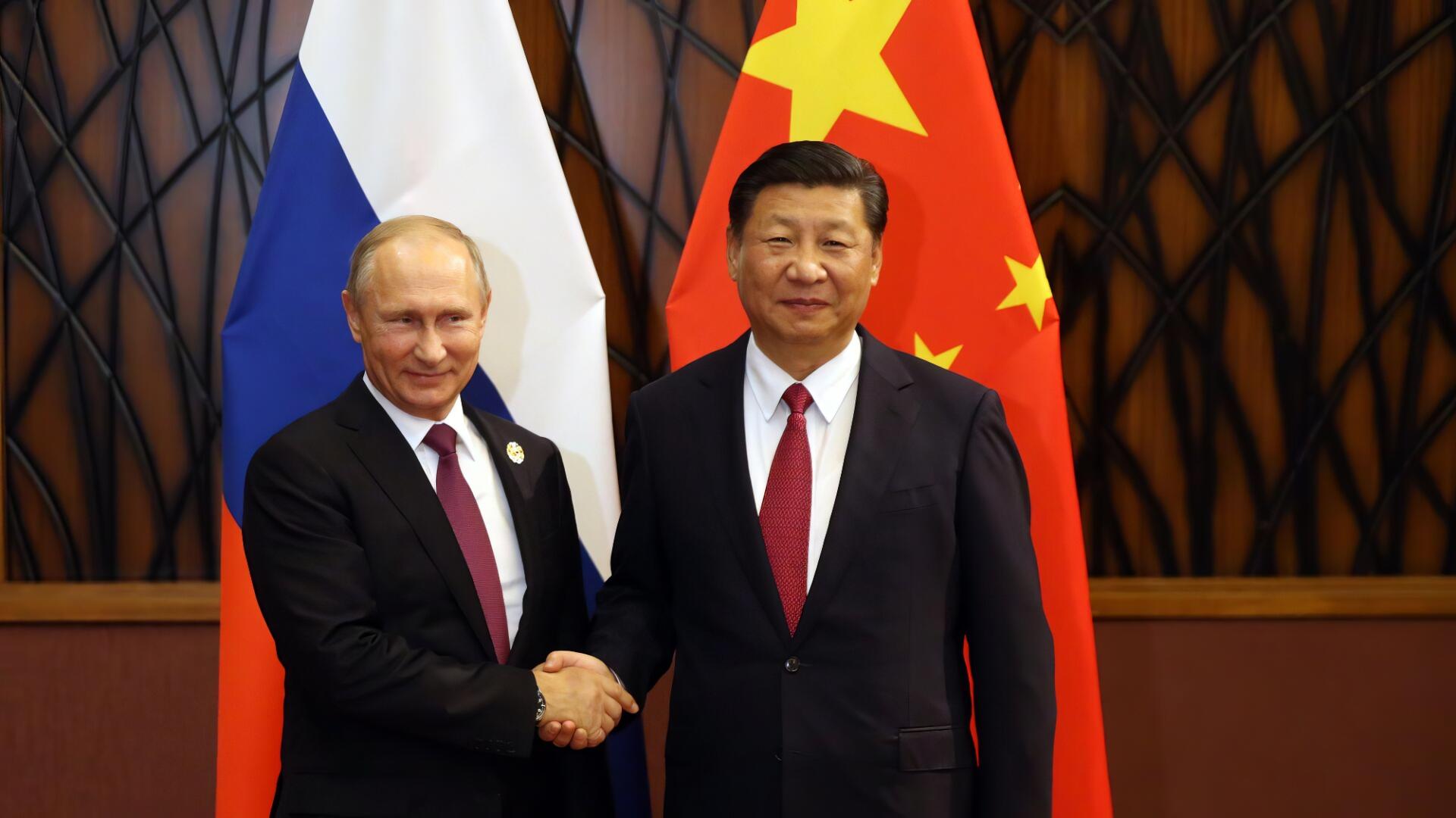 Two men in dark suits shake hands before Chinese and Russian flags, HD desktop wallpaper background.