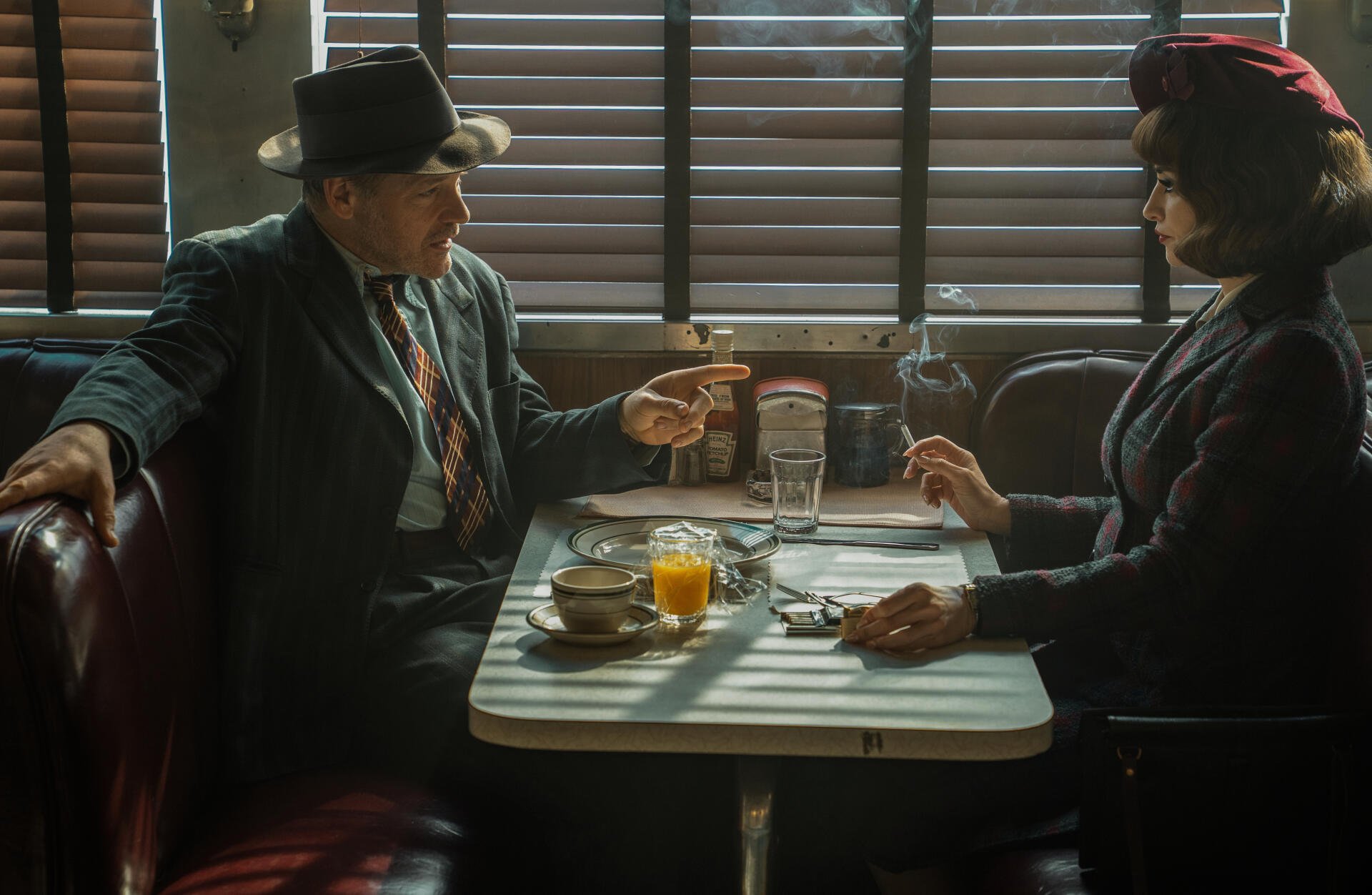 Movie The Bride!: two noir-dressed figures face off in a shadow-striped diner booth—man in fedora pointing, woman in dark hat holding a fork; 5K Ultra HD PC desktop wallpaper/background.