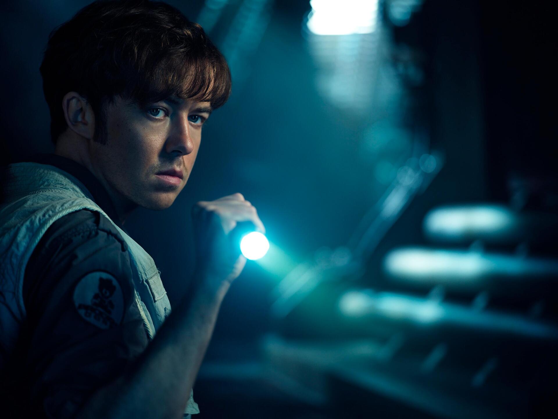 TV show character from Alien: Earth holds a flashlight in a dark, moody scene — 2K Quad HD PC desktop wallpaper background.