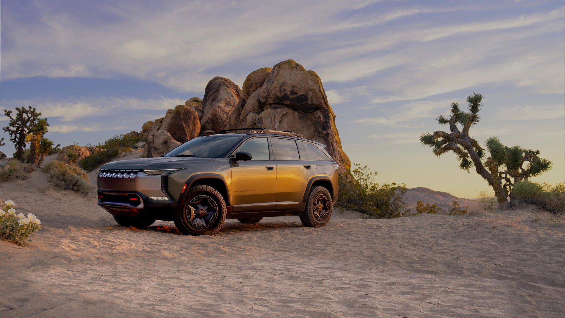 4K Ultra HD PC desktop wallpaper and background: Jeep Wagoneer S parked on desert sand at sunset beneath a rocky outcrop and Joshua trees.