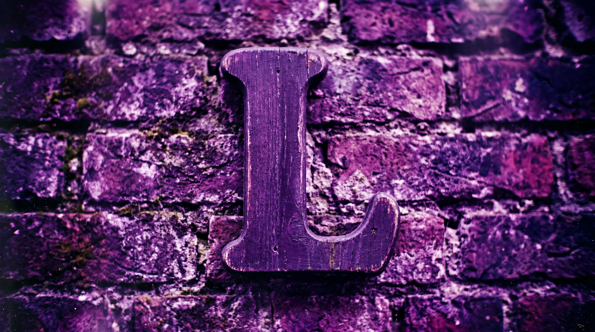 5K Ultra HD PC desktop wallpaper of the letter L (alphabet): carved wooden L mounted on a textured purple brick wall.