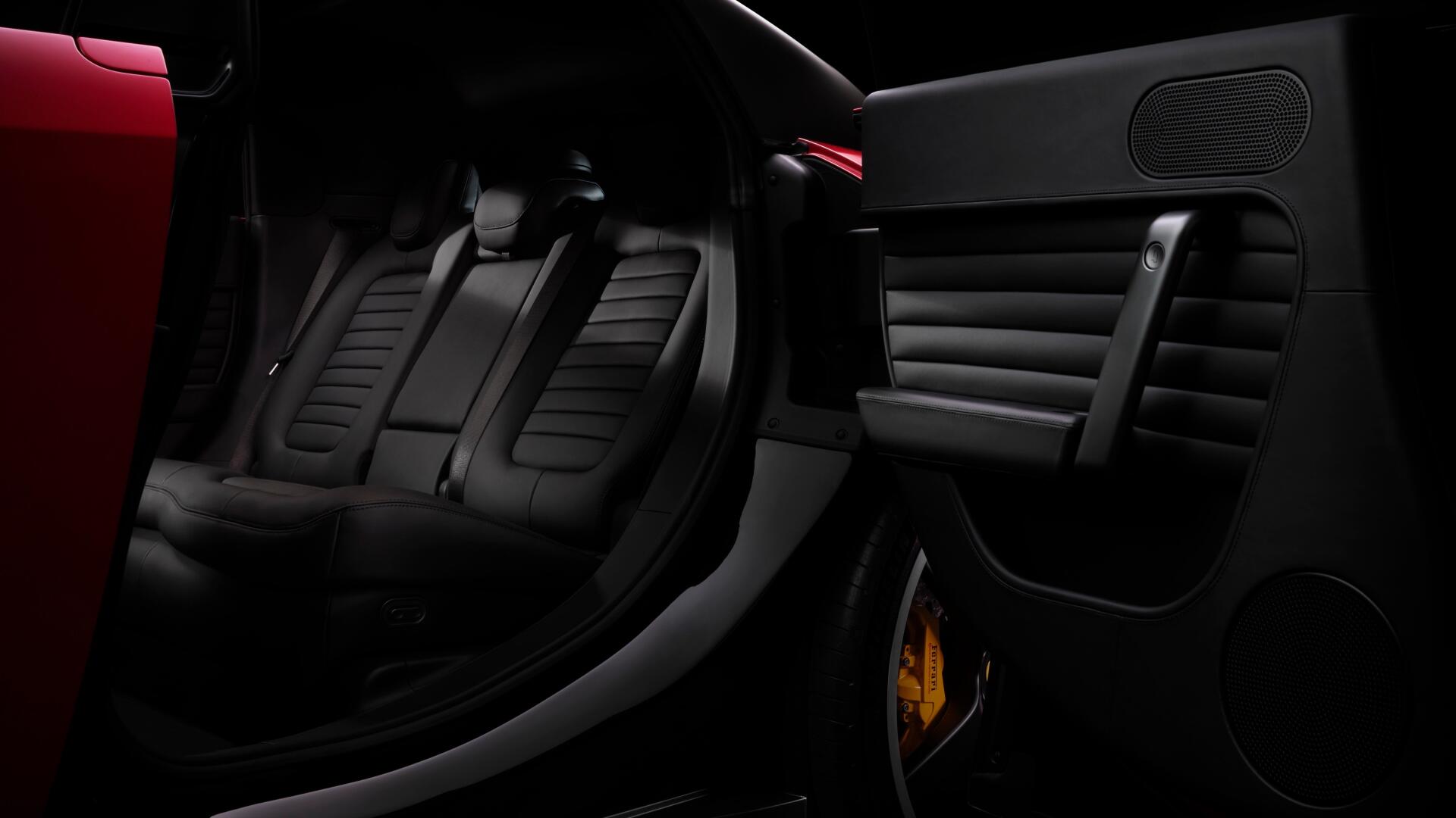 Ferrari Luce interior close-up: black leather seats, sculpted door panel and red exterior trim, 4K Ultra HD PC desktop wallpaper background.