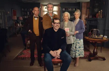 Movie still — The Thursday Murder Club: four older adults and one man posed in a warm library setting. 4K Ultra HD PC desktop wallpaper/background.