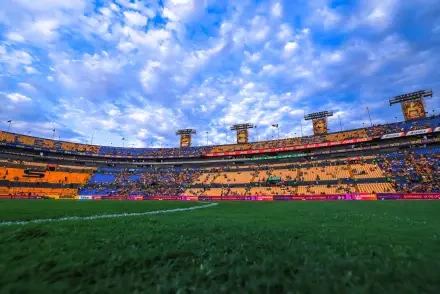 HD PC desktop wallpaper: panoramic view of Cruz Azul stadium and soccer field, lush green pitch beneath a dramatic cloud-filled sky.