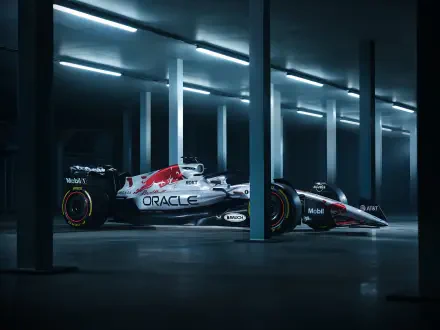 Red Bull RB21 F1 race car in a dim, modern garage with dramatic lighting — 2K Quad HD PC desktop wallpaper highlighting the sleek Red Bull race vehicle and livery.